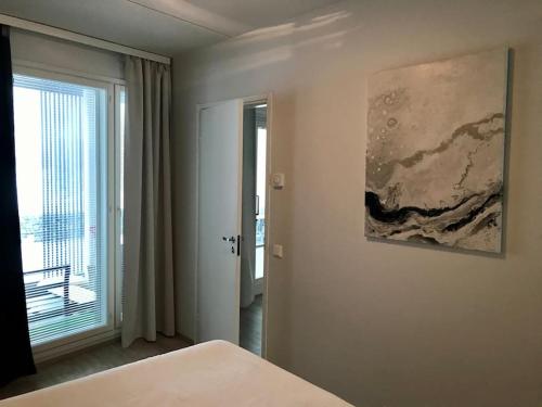 1 dormitorio con 1 cama y una pintura en la pared en Kaksio järvinäkymällä - Two room flat by the lake, en Jyväskylä