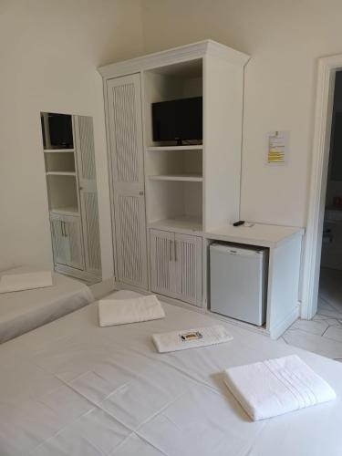 a white room with two white towels on the floor at Jequitiba Hotel Frente ao Mar in Guarujá