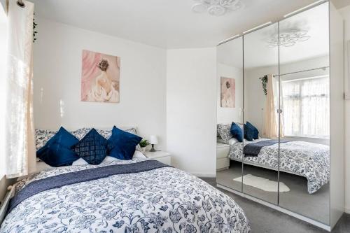 a bedroom with a bed with blue pillows and a mirror at MOYDOM Cosy Apt sleeps 4 with self breakfast & carpark in Redbridge