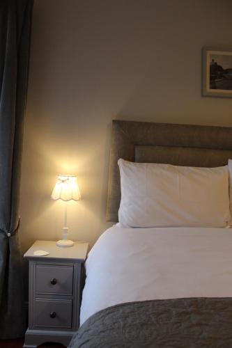 a bed with a nightstand with a lamp on it at Madelines Accommodation in Tinahely