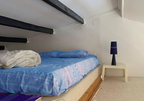 Bett mit blauer Bettdecke und Beistelltisch in der Unterkunft Studio Mezzanine La vie en bleu- Vue mer Deauville in Deauville