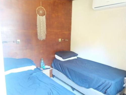 1 dormitorio con 2 camas con sábanas azules y lámpara de araña en Con piscina a 3 cuadras de la playa, en Balneario Argentino