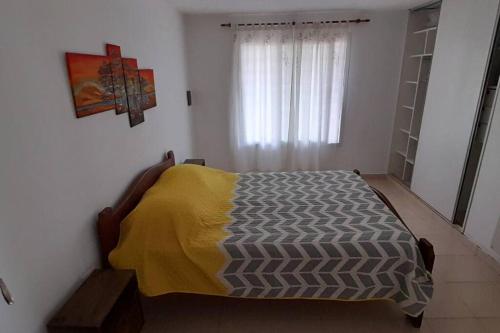 Un dormitorio con una cama con una manta amarilla. en Casa con vista a las sierras en Santa María