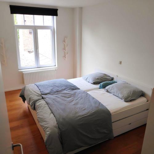 a bed in a white room with a window at SMAK (Met ruim & rustig terras) in De Panne