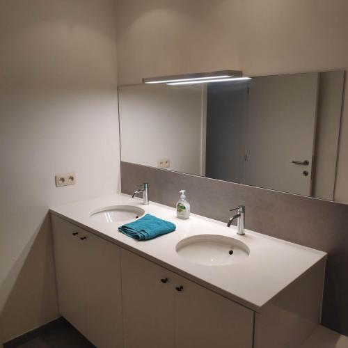 a bathroom with two sinks and a large mirror at SMAK (Met ruim & rustig terras) in De Panne