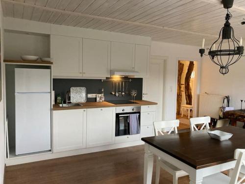 a kitchen with white cabinets and a table and a dining room at Schwedenchalet am Edersee in Vöhl