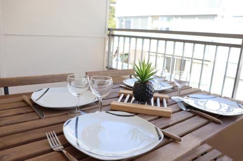 une table en bois avec des assiettes et des verres à vin sur un balcon dans l'établissement Confort - Appartement Cosy - Proche Mer ***, à Vallauris
