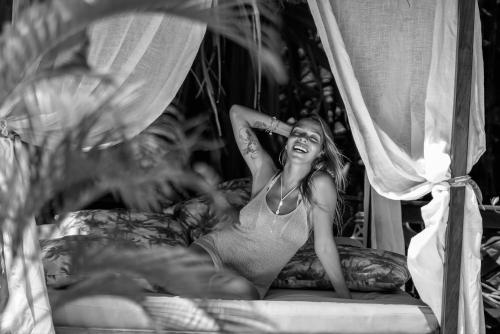 a woman in a dress laying on a bed at ThalassaGarden Hotel - Pousada in Pipa