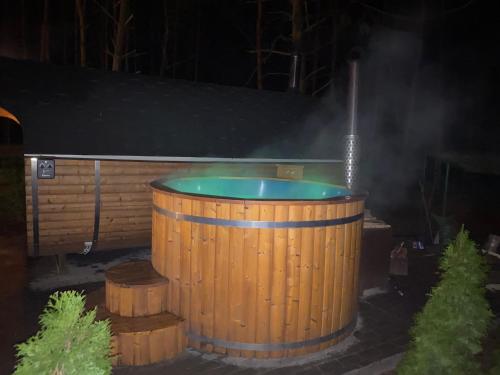 Domki Wiosełko في Cieksyn: حوض استحمام ساخن في برميل خشبي مع الدخان