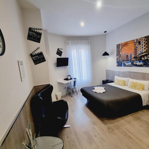 a bedroom with a black bed and a chair at Hostal Lauria in Madrid