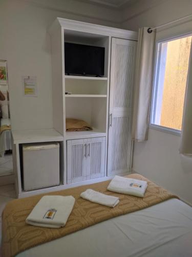 a bedroom with a bed with two towels on it at Jequitiba Hotel Frente ao Mar in Guarujá
