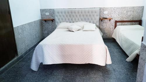 a small bedroom with two beds with white sheets at Portal de las Viñas in Cafayate