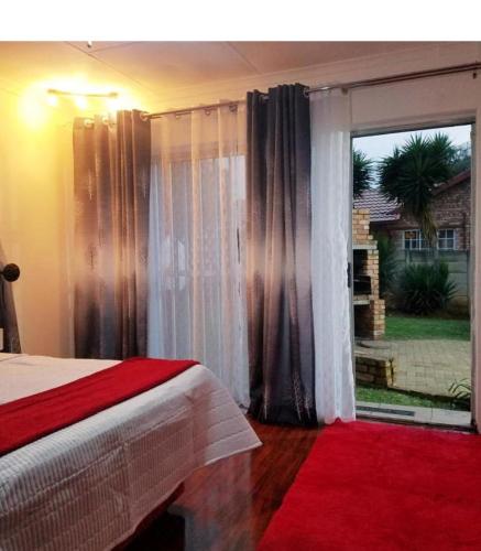 a bedroom with a bed and a large window at The Link on Bonsai in Kempton Park