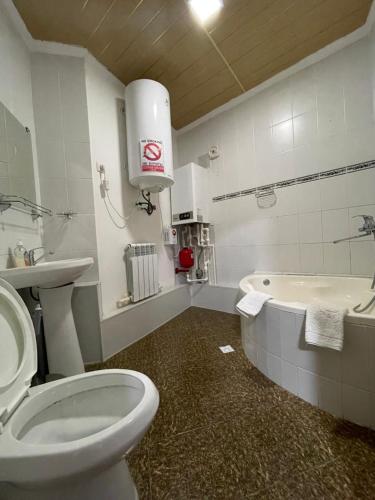 a bathroom with a toilet and a sink and a tub at Hotel Al Mansur in Bukhara