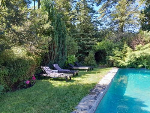 a yard with two benches and a swimming pool at Refugio369cl - LodgeTenisPuconcl in Pucón