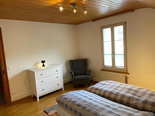 a bedroom with two beds and a chair and a dresser at Interlaken Apartments in Interlaken