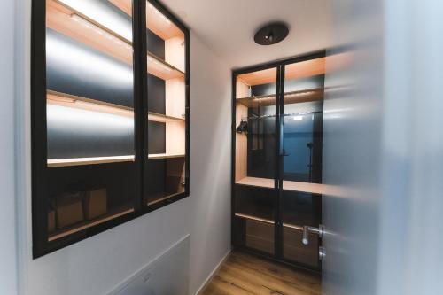 pasillo con puertas de cristal negro y suelo de madera en Triangle City Apartment II, en Viena