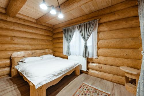 a bedroom with a bed in a log cabin at Rustic Chalet in Călăţele