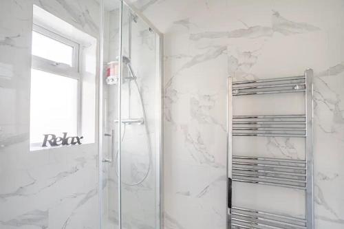 e bagno con doccia e pareti in marmo bianco. di MOYDOM Cosy Apt sleeps 4 with self breakfast & carpark a Redbridge