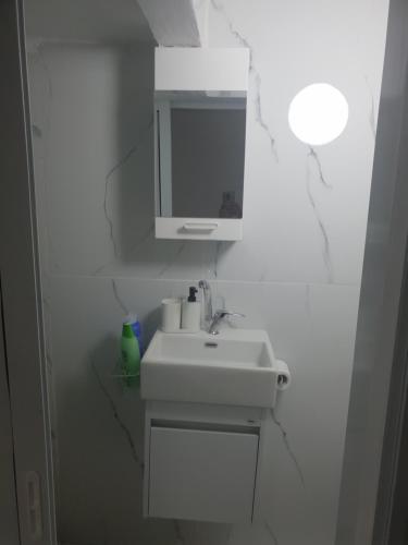 La salle de bains blanche est pourvue d'un lavabo et d'un miroir. dans l'établissement Nitra rooms, à Neve Zohar