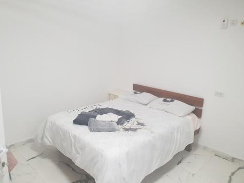 ein weißes Bett mit weißer Bettwäsche und Kissen darauf in der Unterkunft Nitra rooms in Neve Zohar