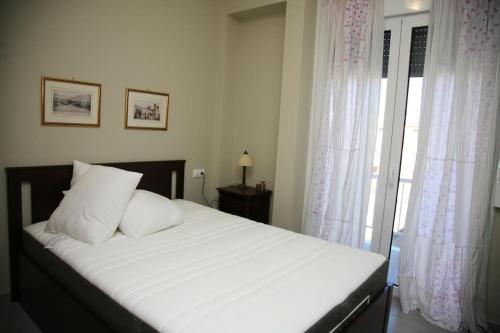 Schlafzimmer mit einem Bett mit weißer Bettwäsche und einem Fenster in der Unterkunft Lovely sea front apartment in Itea