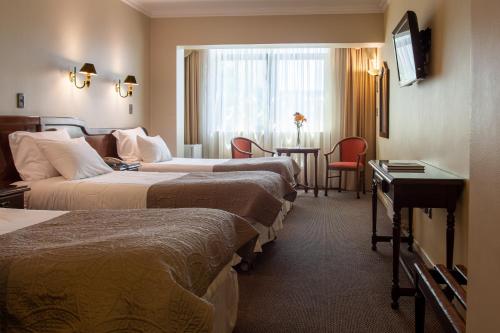 Habitación de hotel con 3 camas y mesa en HOTEL EL DORADO, en Concepción