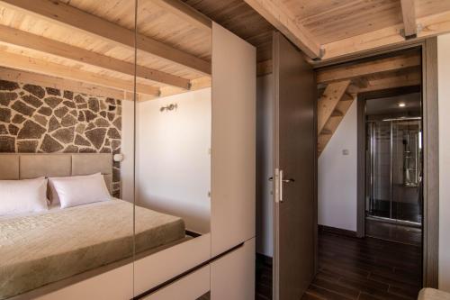 Dormitorio con paredes de cristal, cama y puerta de cristal en Leo's Stone made Villa!, en Karavádhos