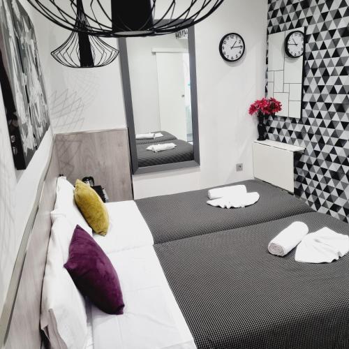 a bedroom with two beds and a mirror at Hostal Lauria in Madrid