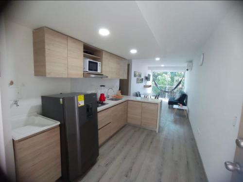 a kitchen with a black refrigerator and wooden cabinets at Apartamentos Dreams TR in Santa Marta
