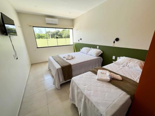 a hotel room with two beds and a window at Pousada Primavera in Parnaíba