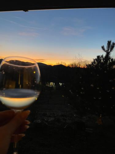 a person holding a glass of wine with the sunset in the background at Vila Xenos Loft Karakter Zlatibor in Zlatibor