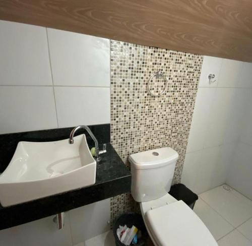 a bathroom with a white toilet and a sink at Chalé Guaramiranga-CE in Guaramiranga