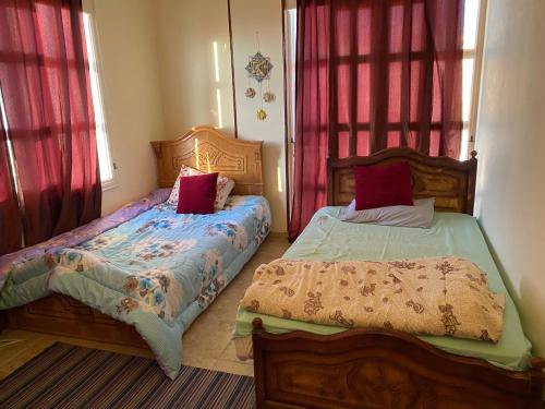 2 camas en un dormitorio con cortinas rojas en PORTO HILL en Hurghada