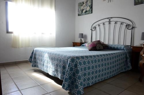 a bedroom with a bed with a blue blanket and a window at Villa Estrella in Tijarafe