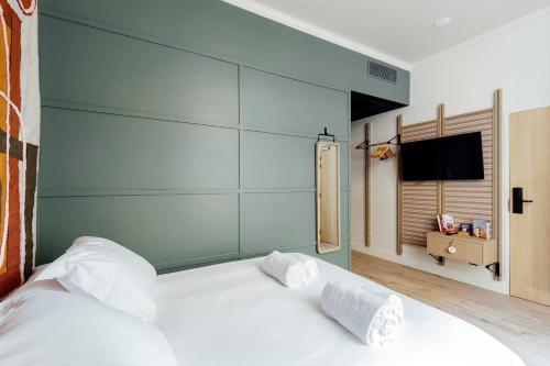 a bedroom with a white bed with a blue wall at Hôtel Préfecture - Entrée autonome, réception en ligne - Encore Mieux in Limoges