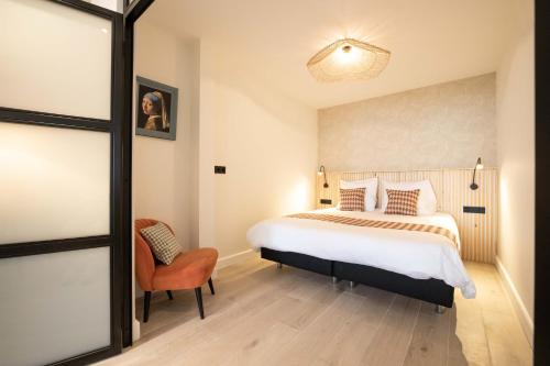 a bedroom with a large bed and a chair at Four Star Apartments - Badhuisstraat 6 in Scheveningen