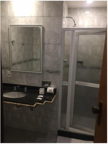 a bathroom with a sink and a shower with a mirror at Tower Icaraí Hotel in Niterói