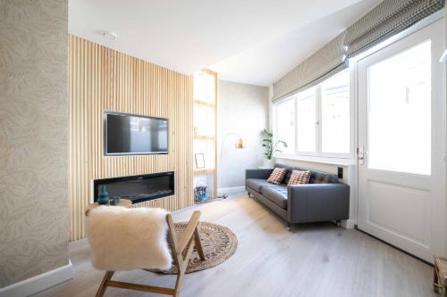 a living room with a couch and a television on a wall at Modern two bedroom apartment close to the beach in Scheveningen