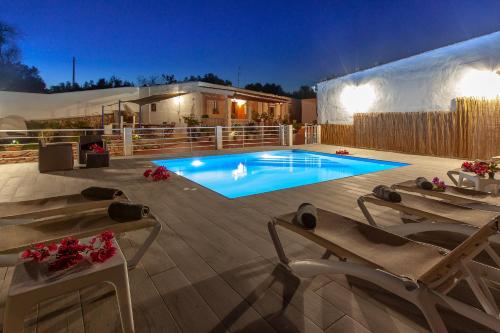 a swimming pool in a backyard at night with two lounge chairs at VillaBlanca in Sant Rafael