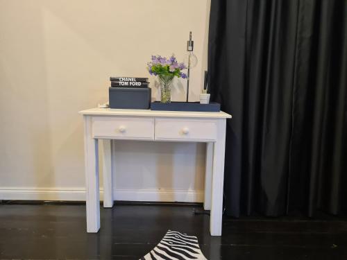 a white table with a vase of flowers on it at Smithgrove Guesthouse in Pietermaritzburg