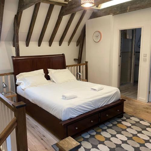 um quarto com uma cama com lençóis brancos e um relógio em Loaf 3 at The Old Granary Converted Town Centre Barn em Beverley
