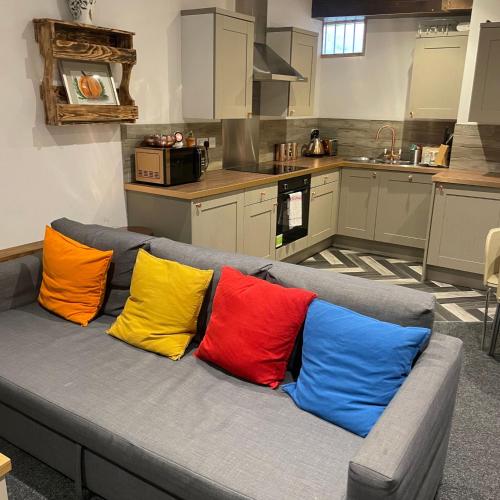 - quatre oreillers colorés sur un canapé gris dans une cuisine dans l'établissement Loaf 3 at The Old Granary Converted Town Centre Barn, à Beverley