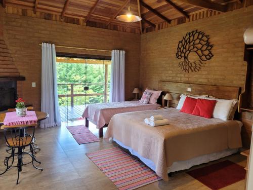 a bedroom with two beds and a table and a window at Estância Liberdade in Santo Antônio do Pinhal