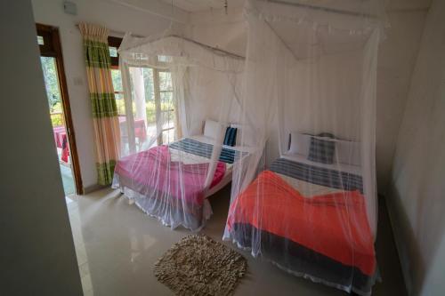 two beds in a room with white walls at Nature's Glow Home Stay AND RESTAURANT in Ella