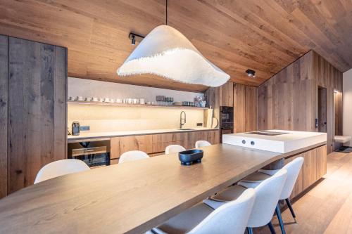 a kitchen with a large wooden table and white chairs at Villa Liesl by ALPS RESORTS in Haus im Ennstal