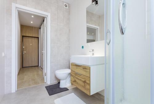 ein Badezimmer mit einem weißen Waschbecken und einem WC in der Unterkunft Nyvky like Home in Kiew