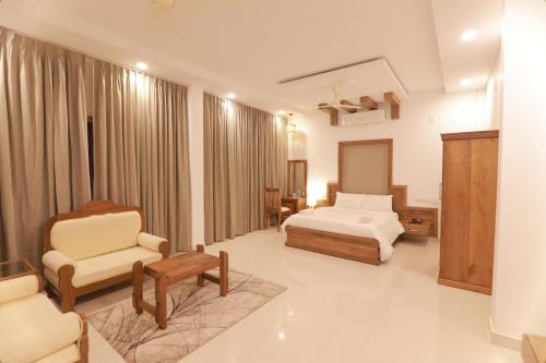 a hotel room with a bed and a chair at OPM INN in Payyannūr