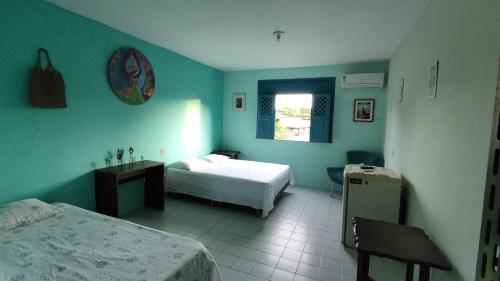 a hotel room with two beds and a window at Refúgio da Mangueira in Barra dos Coqueiros