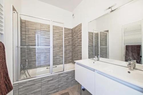 een badkamer met 2 wastafels, een bad en een tubermott bij Villa Riviera Near Disneyland Paris in Chessy